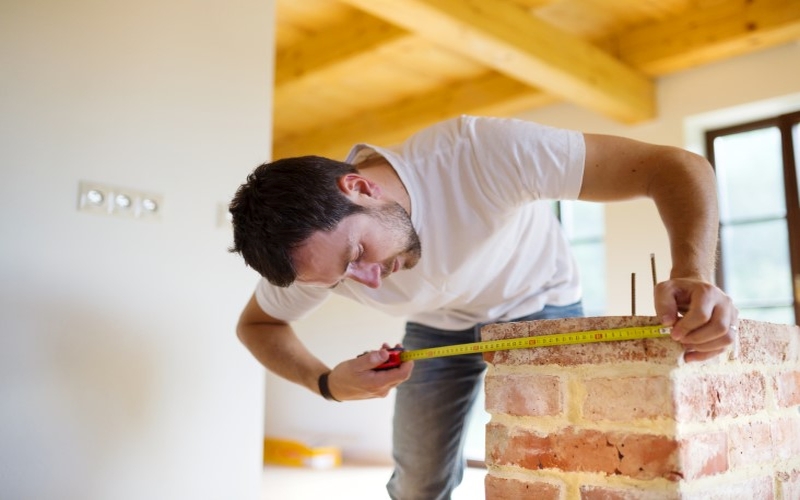 handyman-measures-a-brick-wall-install